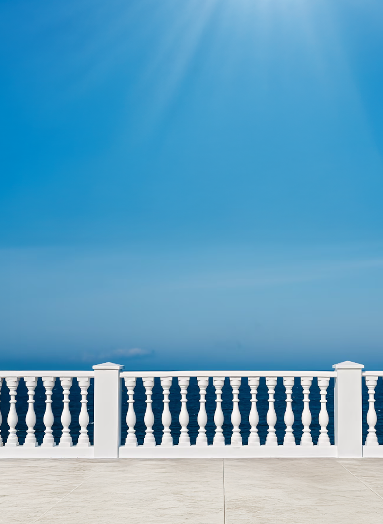 Blue sky with white balcony railing in greek styling in the foreground